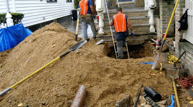 Contractors performing foundation protection and exterior drainage excavation near residential home steps in Nashua, NH